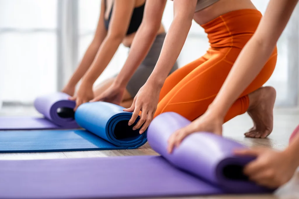 Close up of sportswoman keeping exercise mat in the fitness studio.