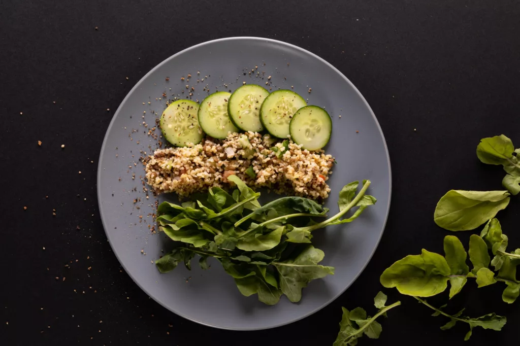 Overhead view of healthy food in plate on black background, copy space